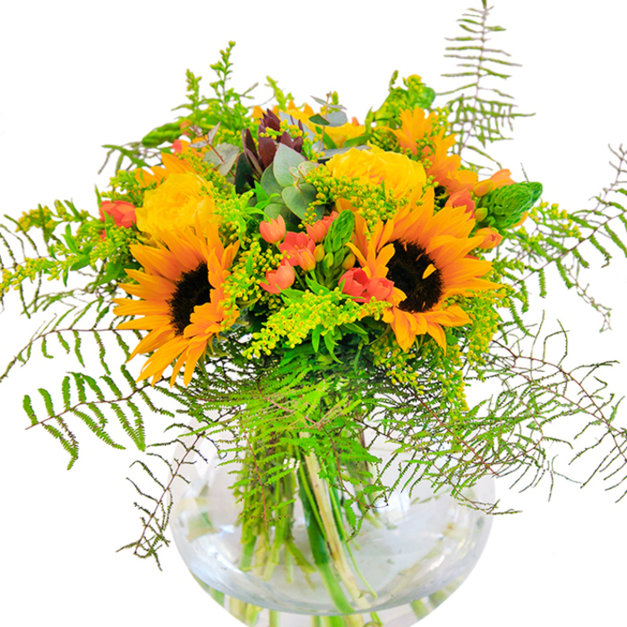 Radiating joy and seasonal richness, this masterful bouquet is a showcase of Tottenham's local floral artistry. The arrangement features proud sunflowers, their sunny faces and velvety brown centres reminiscent of golden evenings over Lordship Recreation Ground. Interlaced among the sunflowers are exquisitely bloomed yellow roses, their petals swirling open in tight, classic spirals that add layers of visual depth and a hint of sweetness. Vivid red Hypericum berries pop among bursts of deep green foliage, echoing the dynamic contrasts in Tottenham's vibrant street life. Waves of delicate greenery-soft ferns, wispy solidago in pale yellow, slender green spikes-cascade outward, giving the bouquet a sense of lively movement and a brush of natural wildness. Bluish-green eucalyptus leaves, almost silvery in the light, infuse a subtle, refreshing note that conjures up memories of peaceful walks along the River Lea. Cradled in a round, transparent glass vase, the submerged stems and glistening water enhance the arrangement's clarity and vitality. This bouquet, perfect for centrepieces or thoughtful gifts to loved ones across Tottenham, creates an atmosphere of warmth and open-hearted happiness-ideal for birthdays, anniversaries, or celebrating simple moments of togetherness. Every detail reflects the fresh, expressive style cherished by Tottenham's community, making it more than just a floral display, but a vibrant expression of local life.